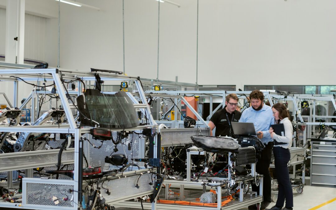 Team of manufacturing professionals reviewing operations on a shop floor in a glass or windshield production facility.